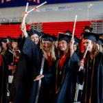 在全球最大的博彩平台2022年毕业典礼上，学生们戴着帽子，穿着长袍，举起文凭庆祝